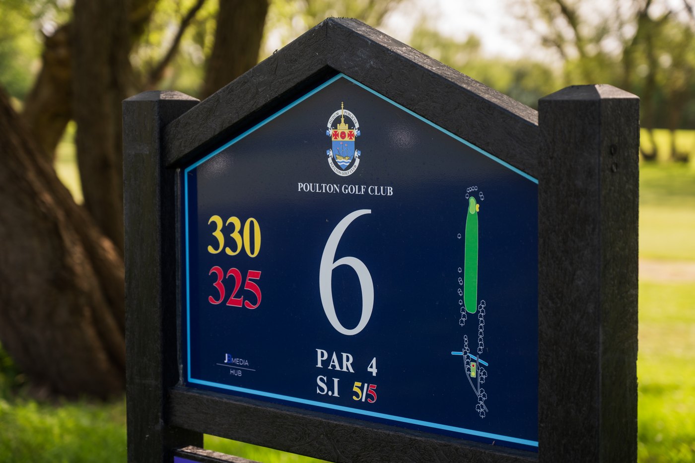 A JB Pro Panel Eco tee sign at Poulton Golf Club: a matte charcoal composite frame with a fine woodgrain texture, around a navy yardage board
